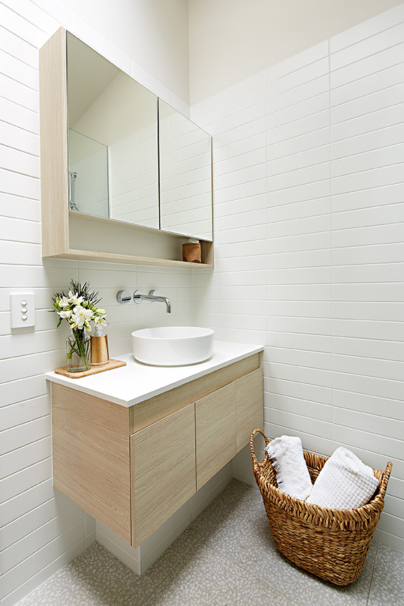 Design ideas for a small beach style 3/4 bathroom in Melbourne with flat-panel cabinets, light wood cabinets, a corner shower, a wall-mount toilet, ceramic tile, mosaic tile floors, a vessel sink and solid surface benchtops.