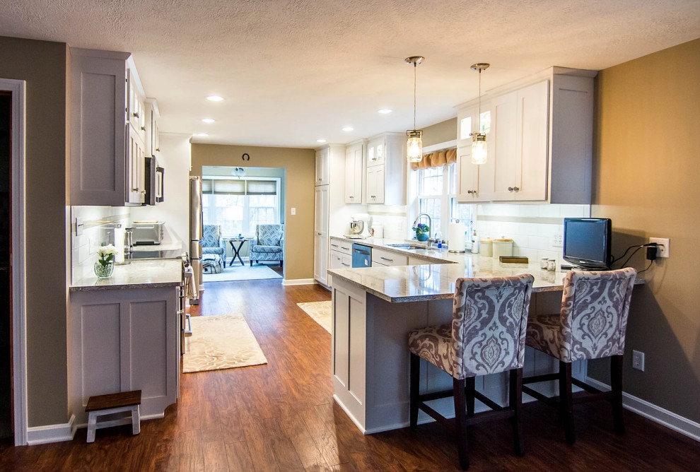 Inspiration for a large transitional galley medium tone wood floor and brown floor enclosed kitchen remodel with an undermount sink, white cabinets, quartzite countertops, white backsplash, stainless steel appliances, a peninsula, shaker cabinets, ceramic backsplash and multicolored countertops