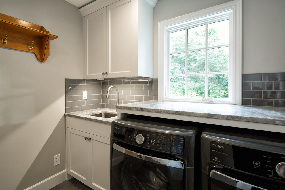 Photo of a mid-sized contemporary single-wall dedicated laundry room in Kansas City with an undermount sink, shaker cabinets, white cabinets, granite benchtops, grey walls, porcelain floors, a side-by-side washer and dryer and grey benchtop.