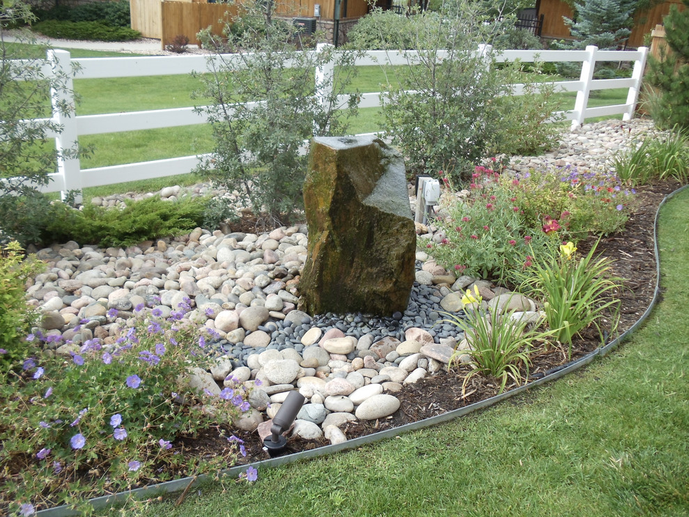 Mid-sized traditional backyard garden in Denver with a water feature and river rock.