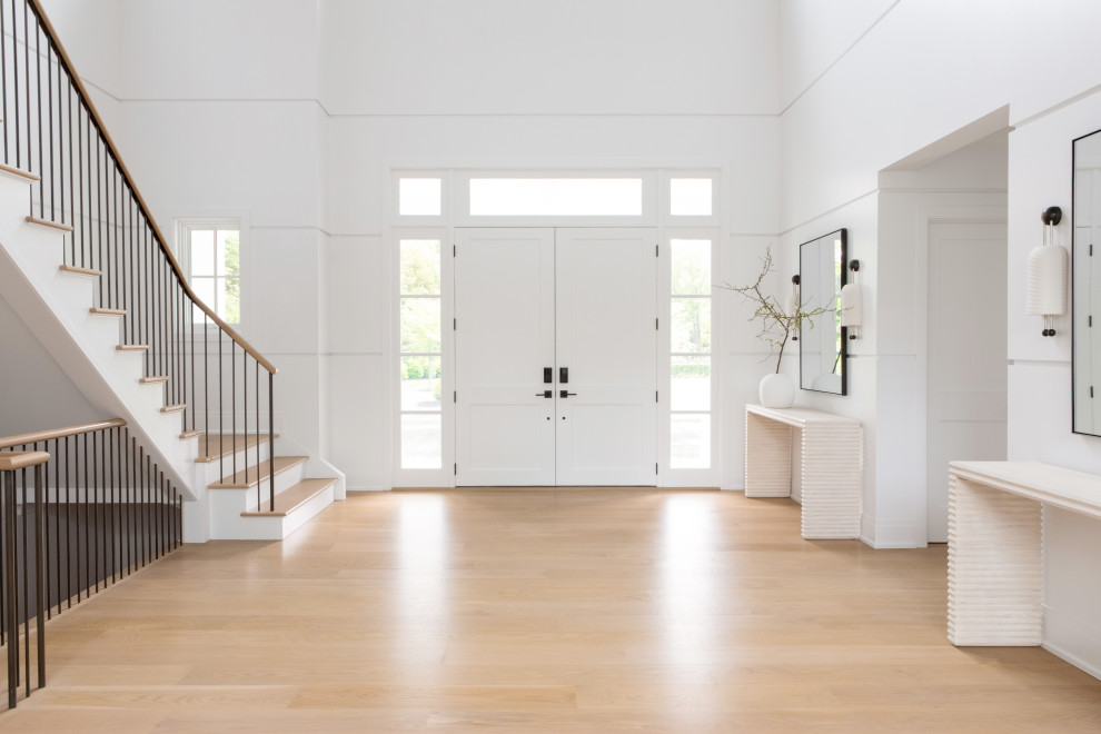 Inspiration for a large transitional front door in New York with white walls, light hardwood floors, a double front door, a white front door, brown floor, vaulted and wood walls.
