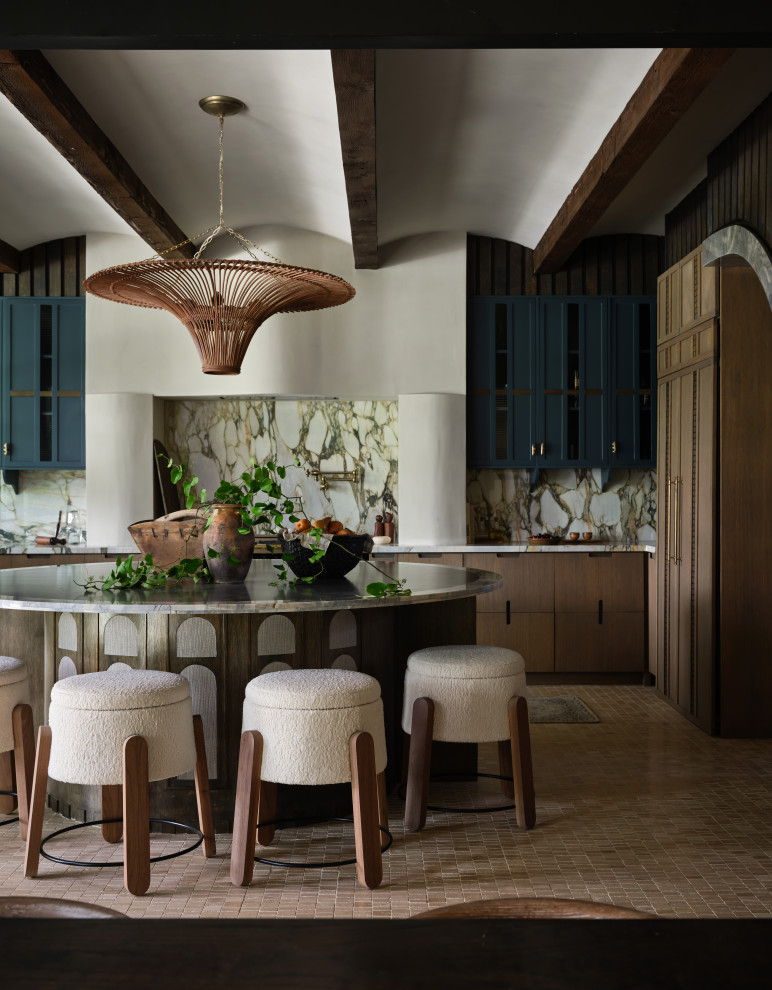 Barrel & Beam - The kitchen at Southlake Manor underwent a full transformation, drawing inspiration from the charm of the South of France while incorporating the Denningtons' personal tastes. A major design feature is the stunning barrelled ceiling, which adds a sense of grandeur and architectural interest. This beautiful ceiling design enhances the space by creating visual height, drawing the eye upward and contributing to the kitchen’s airy and open feel.
The Denningtons’ love for the color blue is woven throughout the kitchen, with custom accents in a rich, deep shade that adds warmth and personality to the space. The cabinetry features a mix of finishes that complement the color palette, creating a balanced, sophisticated look.
At the heart of the kitchen sits a custom, round island—a standout piece designed to be both functional and visually striking. The island, with its unique shape and built-in drawers, provides ample storage while maintaining a sleek, clean aesthetic. It’s an ideal gathering spot for the family and offers a beautiful contrast to the surrounding cabinetry.
The layers of texture throughout the kitchen—from the smooth cabinetry finishes to the intricate details of the island and the natural warmth of the new barrelled ceiling—add depth and dimension. Every element is carefully crafted to elevate the design to the next level, blending style with practicality in a way that reflects the Denningtons' love for sophisticated, yet welcoming spaces.