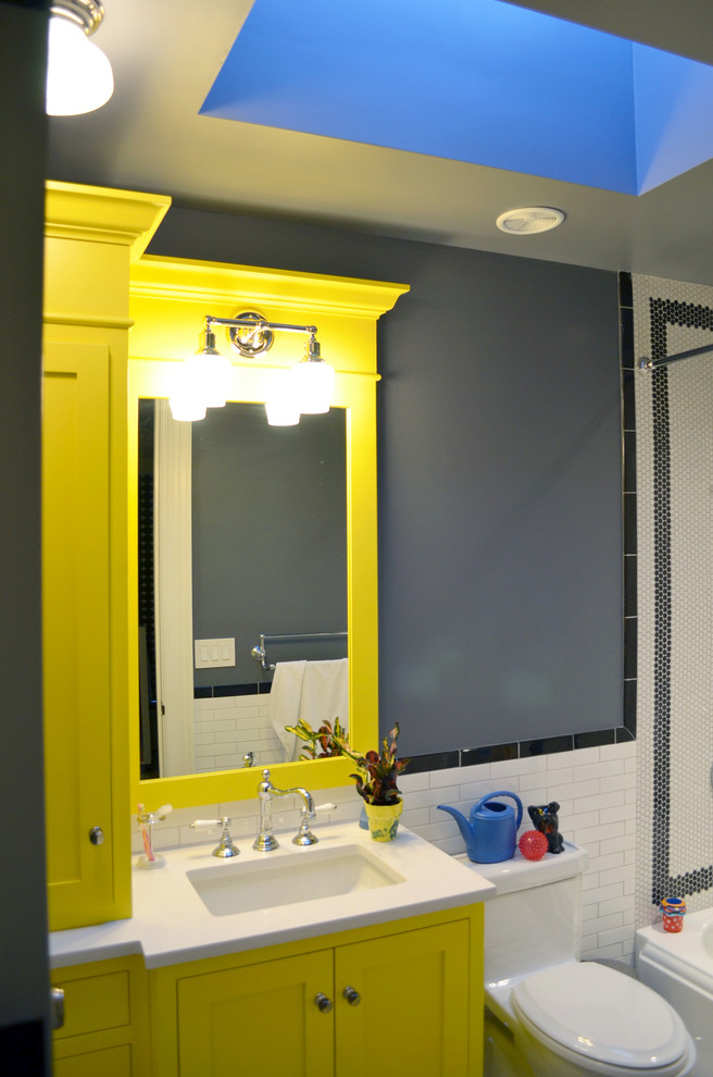 Inspiration for a mid-sized transitional 3/4 bathroom in New York with shaker cabinets, yellow cabinets, an alcove tub, an alcove shower, a one-piece toilet, white tile, subway tile, grey walls, an undermount sink, quartzite benchtops and a shower curtain.