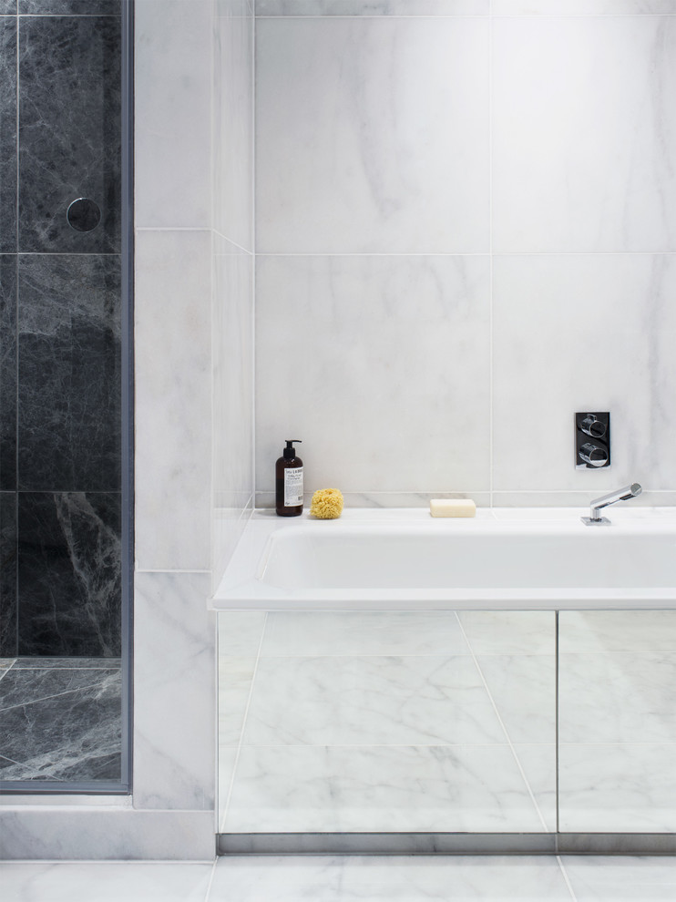 Large modern master bathroom in London with a console sink, flat-panel cabinets, black cabinets, solid surface benchtops, a drop-in tub, an alcove shower, a wall-mount toilet, black and white tile, stone tile, white walls and marble floors.