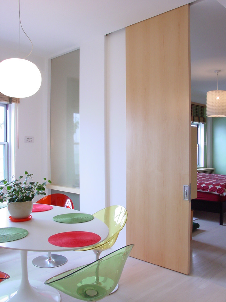 This is an example of a midcentury dining room in New York with white walls and light hardwood floors.