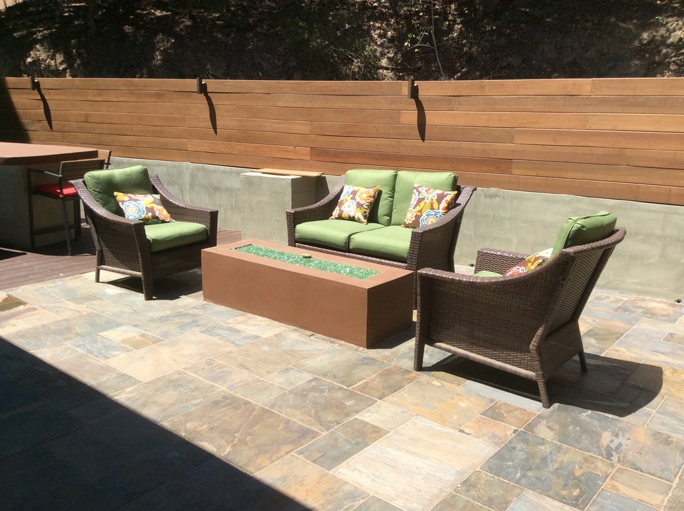 This is an example of a large contemporary front yard patio in Los Angeles with a fire feature, tile and no cover.