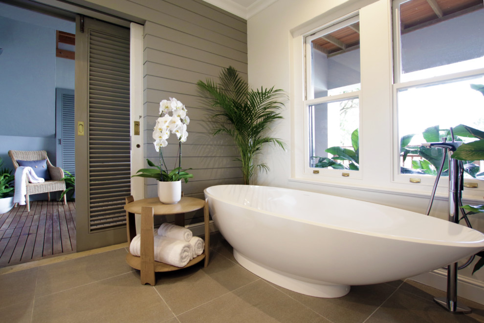 This is an example of a mid-sized beach style master bathroom in Other with light wood cabinets, a freestanding tub, an open shower, a one-piece toilet, gray tile, porcelain tile, grey walls, porcelain floors, a pedestal sink and wood benchtops.
