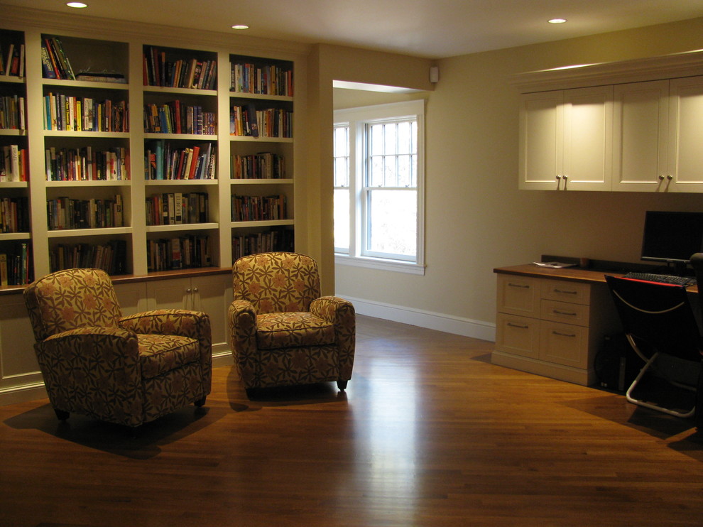 This is an example of a large traditional study room in Boston with yellow walls, dark hardwood floors, no fireplace, a built-in desk and brown floor.