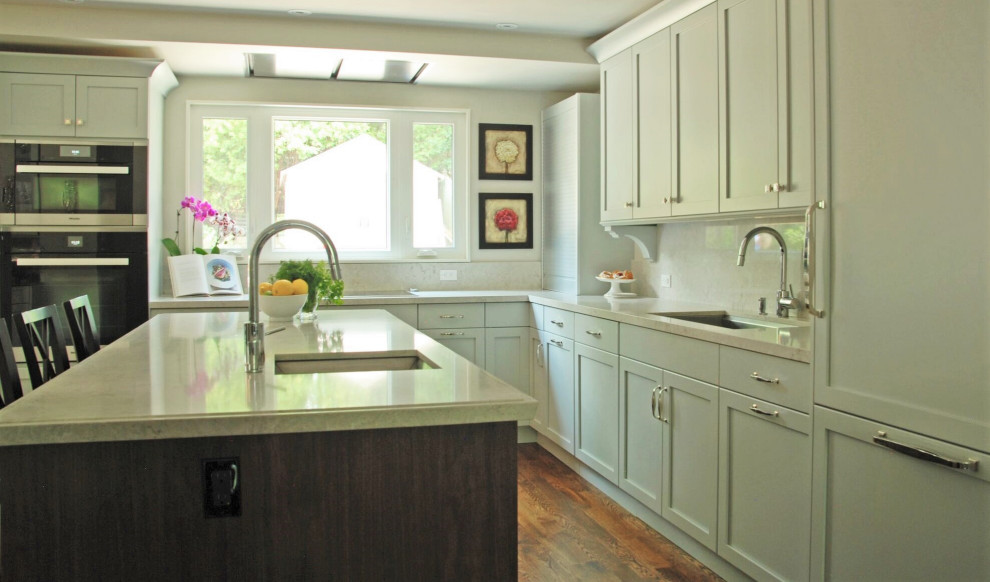Example of a mid-sized transitional l-shaped medium tone wood floor open concept kitchen design with an undermount sink, recessed-panel cabinets, blue cabinets, quartz countertops, white backsplash, quartz backsplash, an island and white countertops
