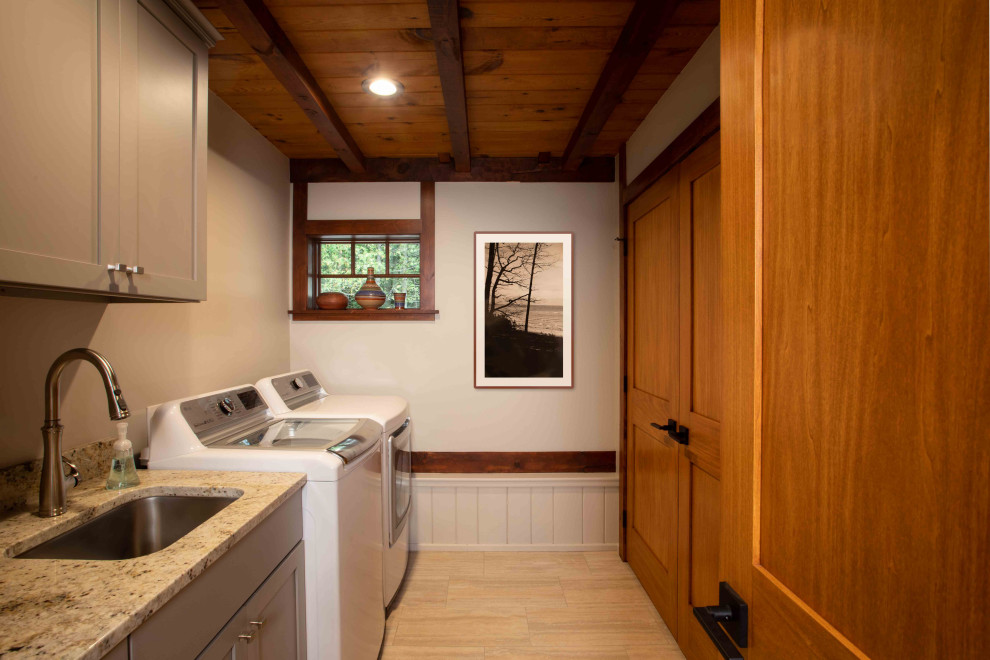 Mid-sized country single-wall dedicated laundry room in Other with an undermount sink, granite benchtops, a side-by-side washer and dryer, multi-coloured benchtop and exposed beam.