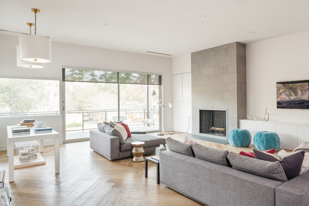This is an example of a contemporary living room in Other with white walls, medium hardwood floors, a standard fireplace and a tile fireplace surround.