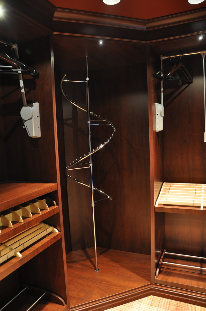 This is an example of a mid-sized traditional gender-neutral dressing room in Dallas with recessed-panel cabinets, dark wood cabinets and carpet.