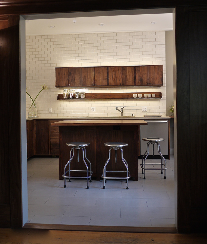 Photo of a mid-sized modern l-shaped separate kitchen in San Francisco with an undermount sink, flat-panel cabinets, dark wood cabinets, white splashback, subway tile splashback, stainless steel appliances, ceramic floors, with island and limestone benchtops.
