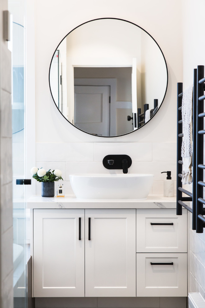 Inspiration for a mid-sized traditional master bathroom in Melbourne with recessed-panel cabinets, white cabinets, a drop-in tub, an alcove shower, a two-piece toilet, white tile, ceramic tile, white walls, ceramic floors, a drop-in sink, marble benchtops, grey floor and white benchtops.