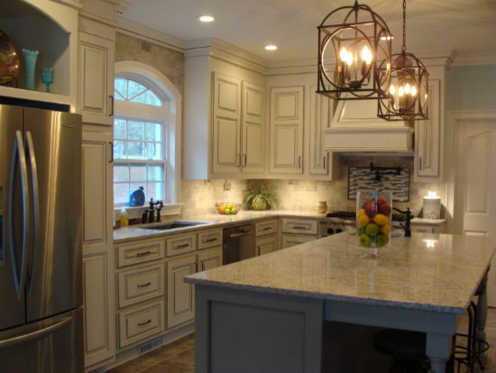 Transitional ceramic tile kitchen photo with an undermount sink, raised-panel cabinets, white cabinets, solid surface countertops, subway tile backsplash, stainless steel appliances and an island