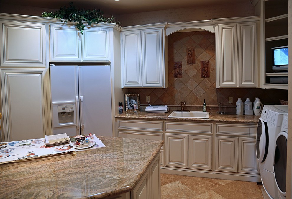Large transitional u-shaped utility room in Phoenix with a drop-in sink, raised-panel cabinets, white cabinets, granite benchtops, travertine floors and a side-by-side washer and dryer.