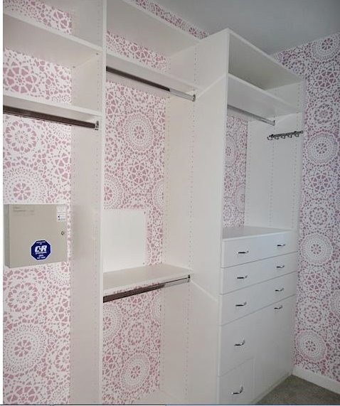 This is an example of a small beach style women's walk-in wardrobe in Los Angeles with flat-panel cabinets, white cabinets, carpet and beige floor.