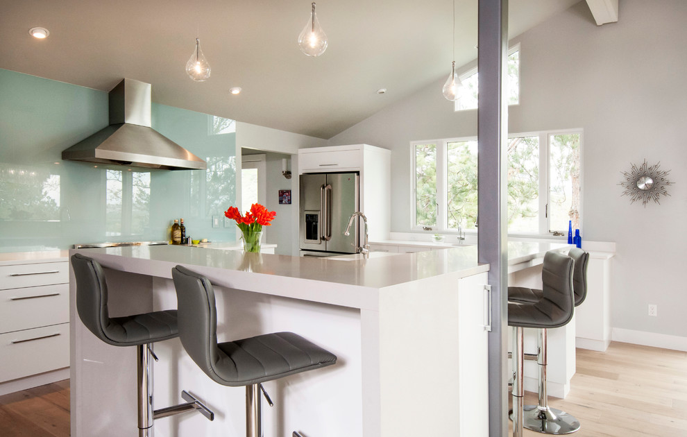 Design ideas for a mid-sized contemporary l-shaped eat-in kitchen in Boise with an undermount sink, flat-panel cabinets, white cabinets, quartzite benchtops, green splashback, glass sheet splashback, stainless steel appliances, light hardwood floors and with island.