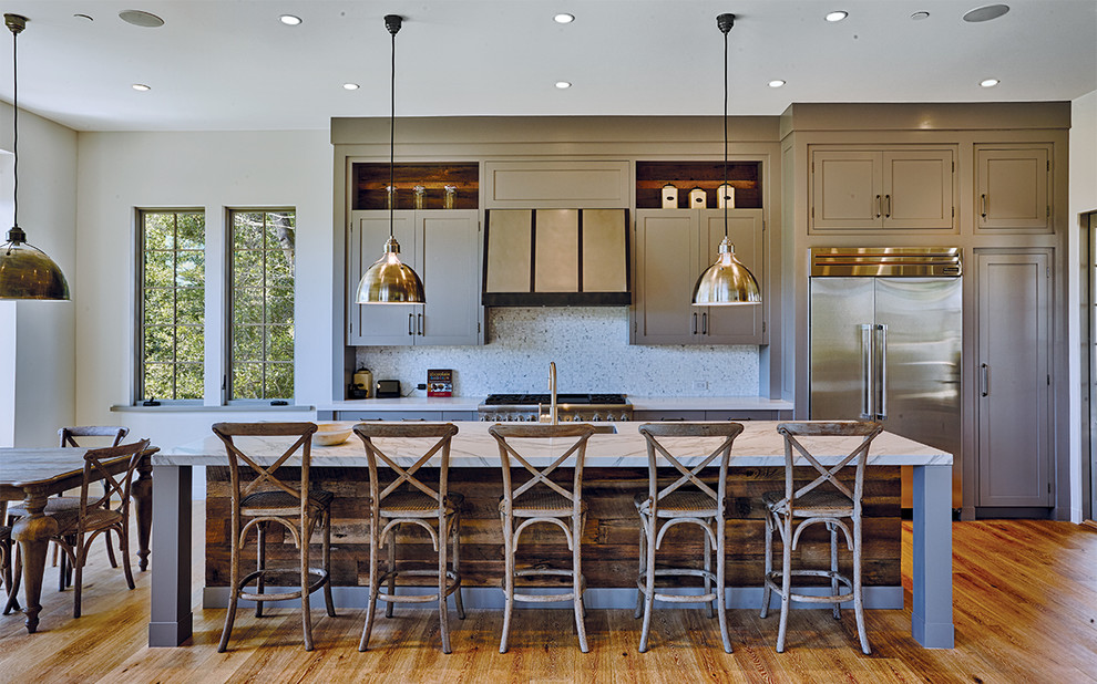 This is an example of a contemporary open plan kitchen in San Francisco with stainless steel appliances, light hardwood floors and with island.