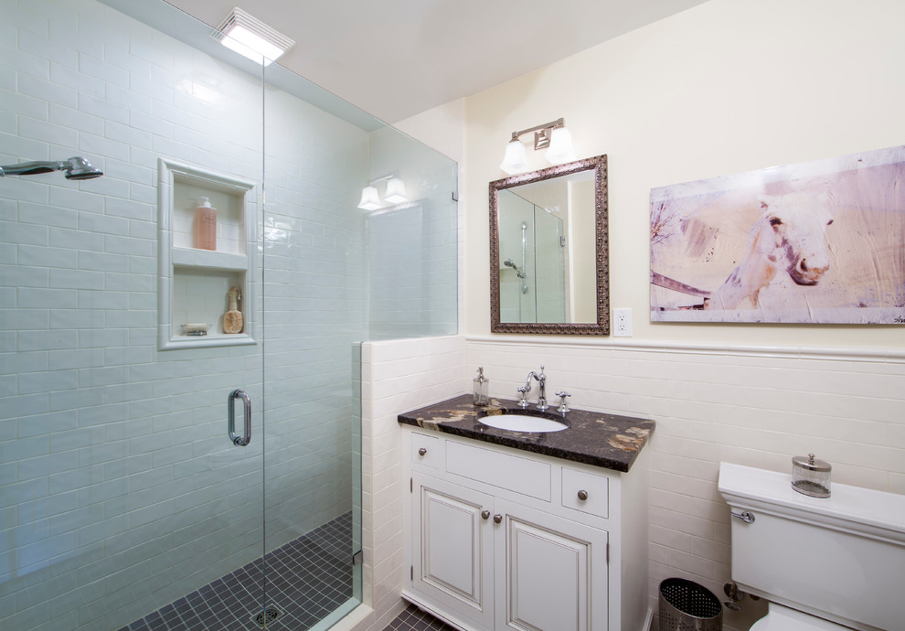 Photo of a mid-sized traditional bathroom in Charlotte with subway tile, raised-panel cabinets, white cabinets, an alcove shower, a two-piece toilet, white tile, beige walls, porcelain floors, an undermount sink, granite benchtops, black floor and a hinged shower door.