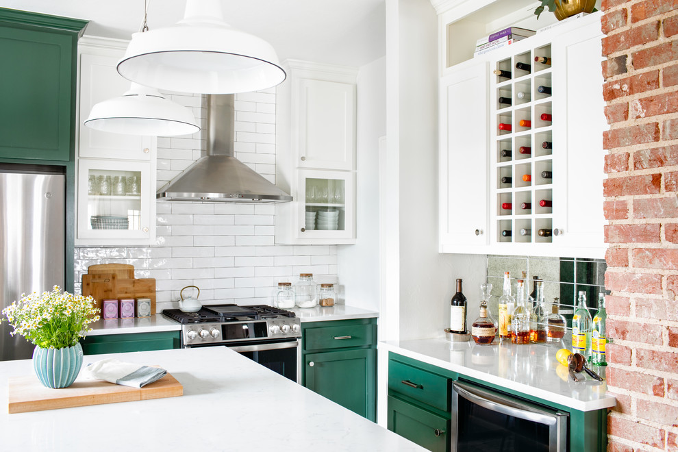 Example of a mid-sized transitional medium tone wood floor and brown floor kitchen design in Chicago with a farmhouse sink, shaker cabinets, green cabinets, quartz countertops, white backsplash, subway tile backsplash, stainless steel appliances, an island and white countertops
