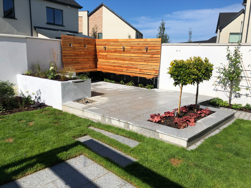 Kleiner Moderner Garten im Sommer, hinter dem Haus mit direkter Sonneneinstrahlung und Natursteinplatten in Dublin