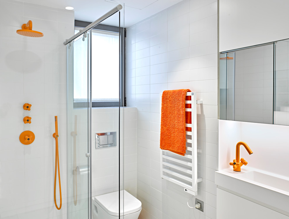 Inspiration for a small beach style 3/4 bathroom in Barcelona with flat-panel cabinets, white cabinets, a corner shower, a wall-mount toilet, white tile, ceramic tile, white walls, an integrated sink and a sliding shower screen.