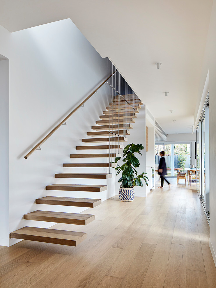 Inspiration for a mid-sized wood floating staircase in Melbourne with cable railing.