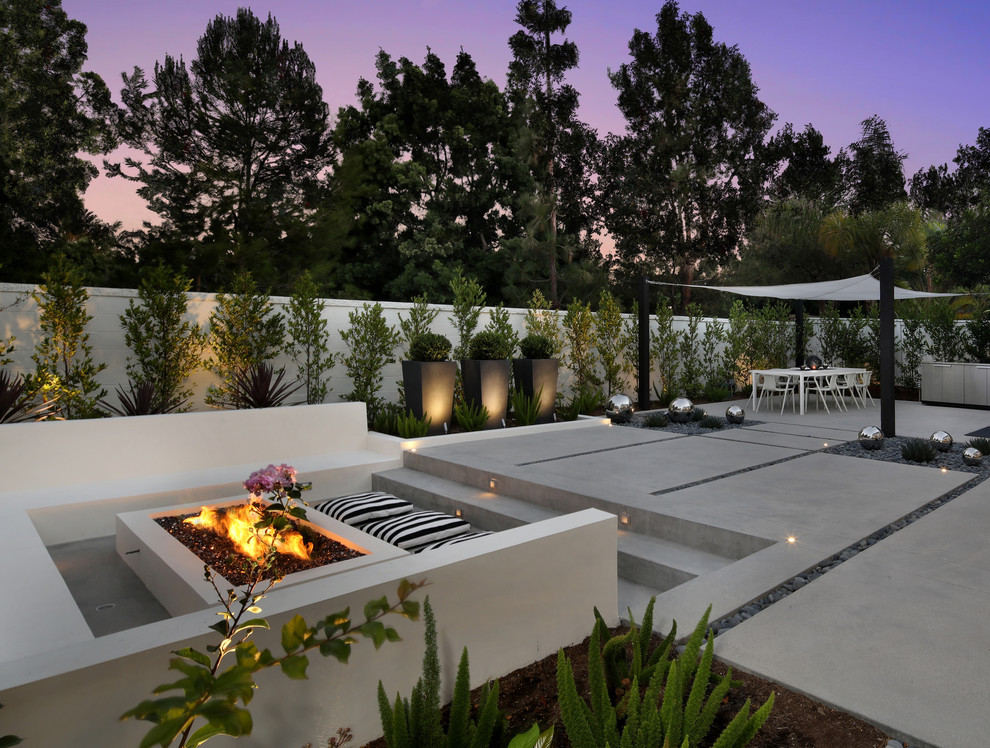This is an example of a large modern backyard patio in Orange County with a fire feature, concrete slab and a gazebo/cabana.