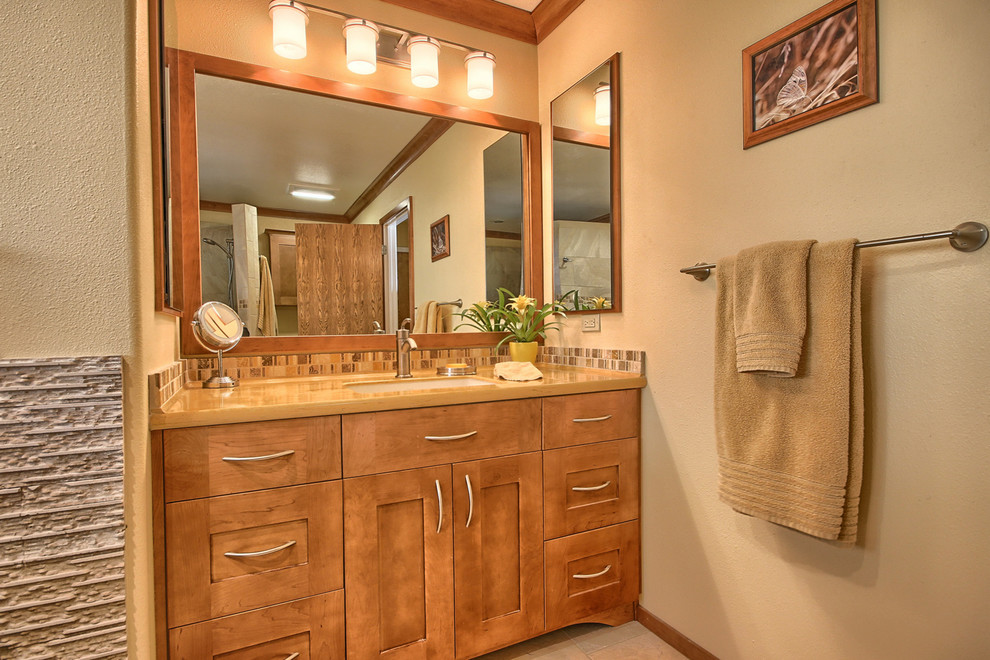 Mid-sized transitional master bathroom in Other with an undermount sink, recessed-panel cabinets, medium wood cabinets, solid surface benchtops, a freestanding tub, an open shower, a two-piece toilet, brown tile, porcelain tile, yellow walls and porcelain floors.
