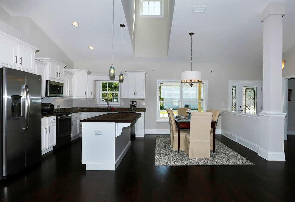 Mid-sized transitional l-shaped dark wood floor eat-in kitchen photo in Orlando with an undermount sink, flat-panel cabinets, white cabinets, granite countertops, stainless steel appliances and an island
