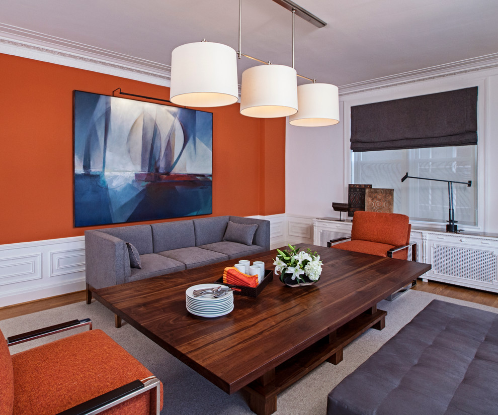 Photo of a modern dining room in Detroit with orange walls and medium hardwood floors.