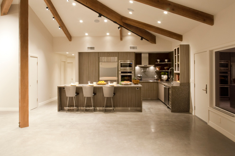 This is an example of a modern l-shaped open plan kitchen in Los Angeles with an undermount sink, flat-panel cabinets, quartz benchtops, stainless steel appliances, concrete floors, with island, grey cabinets, grey splashback and ceramic splashback.