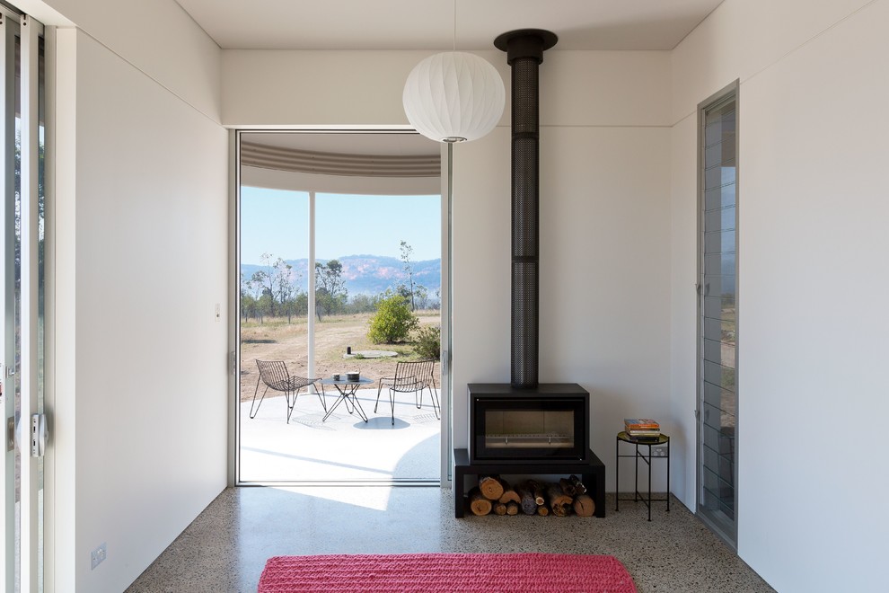 This is an example of a scandinavian living room in Sydney with concrete floors, a wood stove and grey floor.