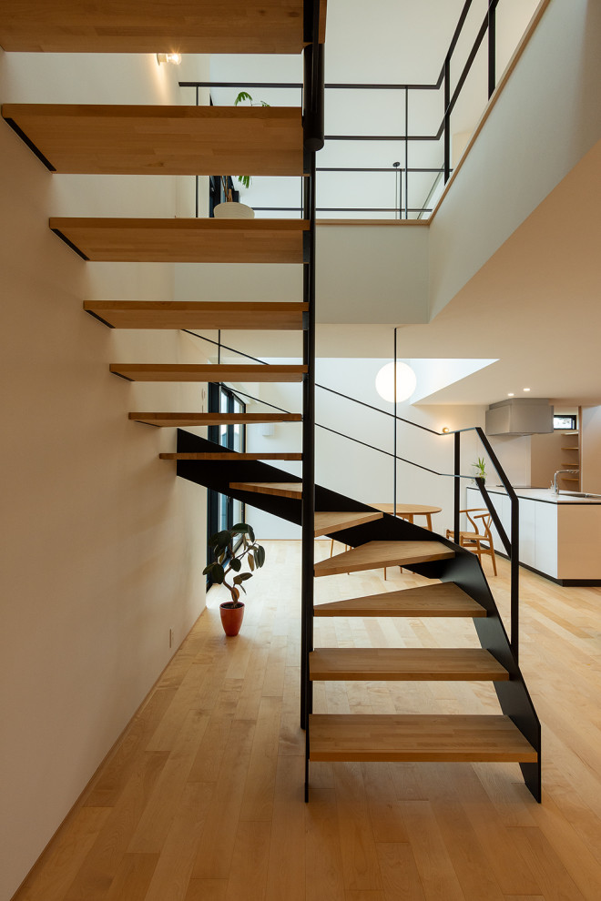 This is an example of an expansive wood floating metal railing staircase in Other with open risers and wallpapered walls.