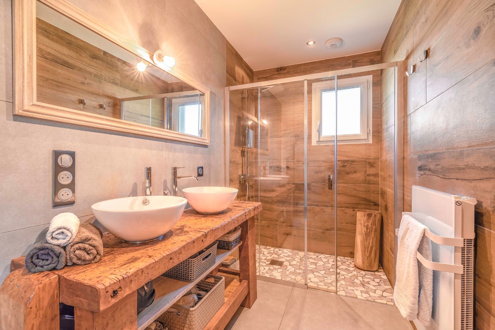 This is an example of a contemporary 3/4 bathroom in Grenoble with open cabinets, medium wood cabinets, an alcove shower, brown tile, grey walls, a vessel sink, wood benchtops, grey floor, a sliding shower screen and brown benchtops.