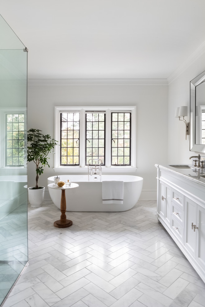 Design ideas for an expansive transitional master bathroom in New York with marble floors, grey floor, recessed-panel cabinets, white cabinets, a freestanding tub, a corner shower, white walls, an undermount sink and white benchtops.