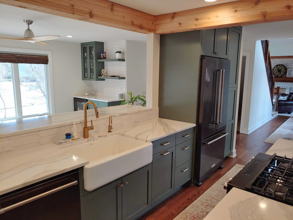 Inspiration for a mid-sized transitional l-shaped dark wood floor eat-in kitchen remodel with a farmhouse sink, recessed-panel cabinets, green cabinets, quartz countertops, white backsplash, black appliances, an island and white countertops