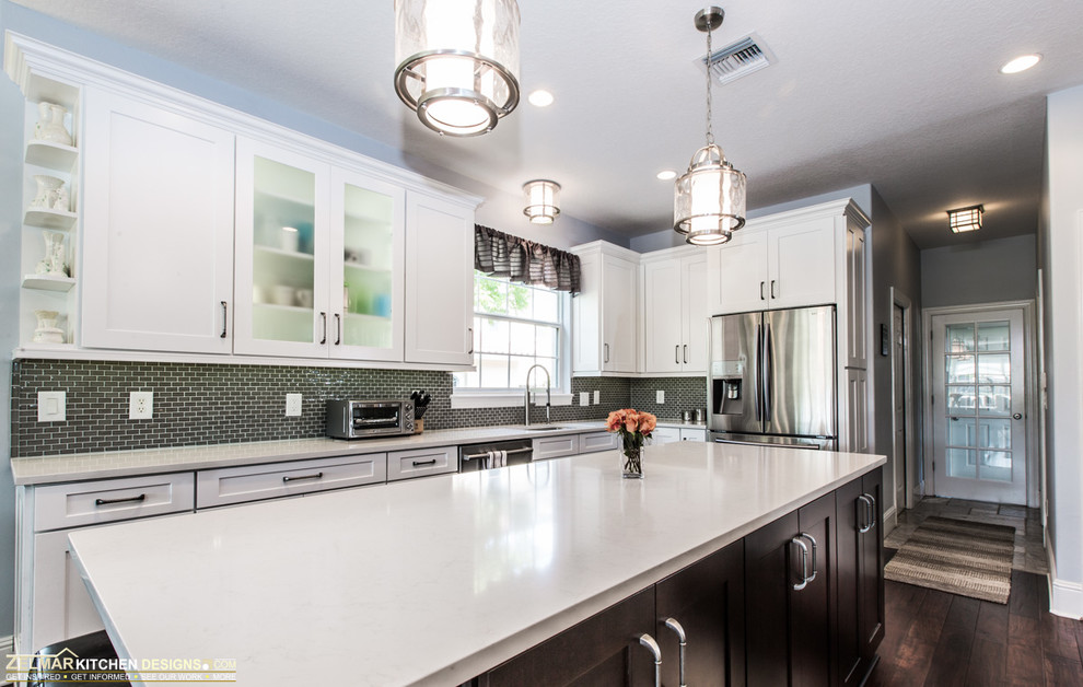 This is an example of a large contemporary u-shaped eat-in kitchen in Orlando with shaker cabinets, white cabinets, with island, an undermount sink, quartz benchtops, green splashback, glass sheet splashback, stainless steel appliances and dark hardwood floors.