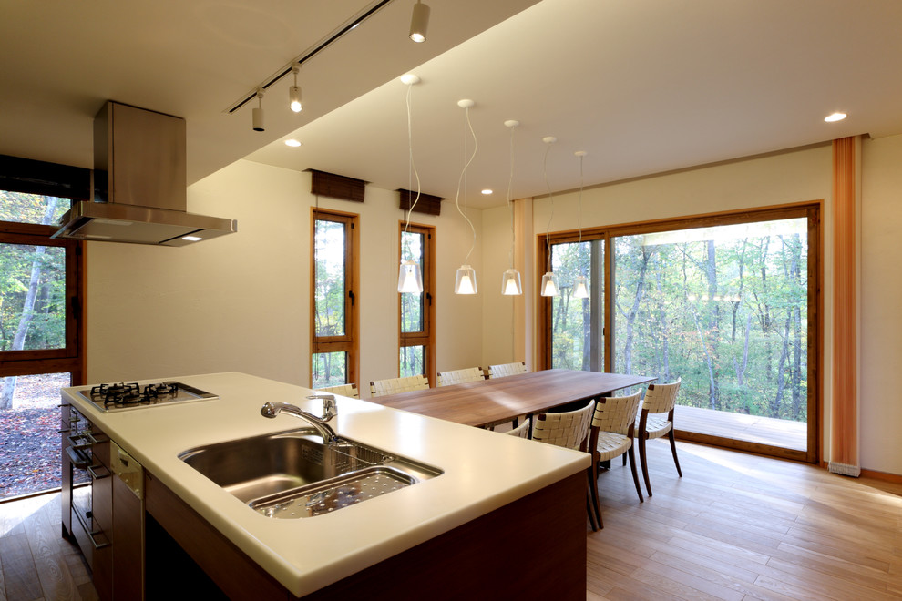 Photo of a large modern eat-in kitchen in Other with an undermount sink, flat-panel cabinets, brown cabinets, marble benchtops, brown splashback, timber splashback, stainless steel appliances, light hardwood floors, with island, beige floor and white benchtop.