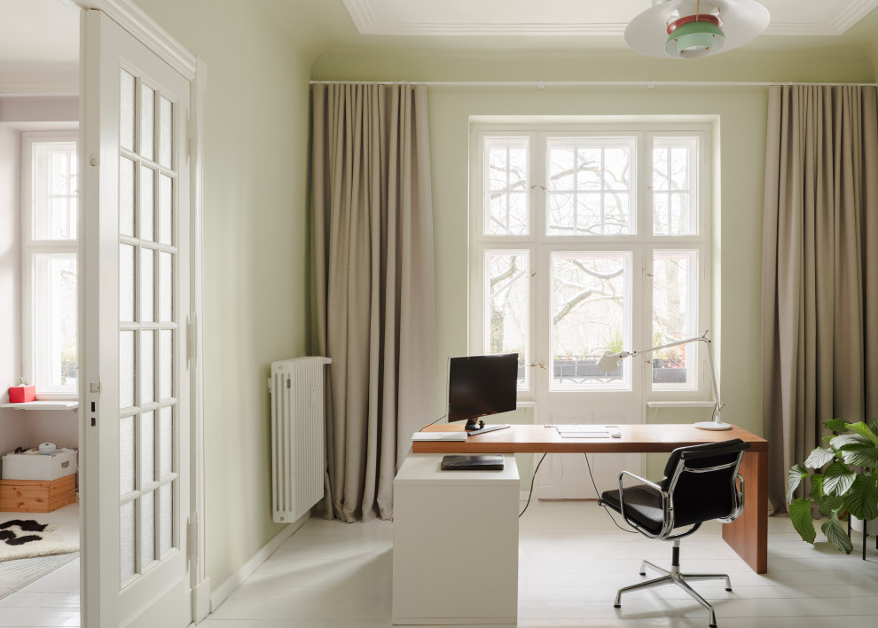 Modernes Arbeitszimmer mit Arbeitsplatz, grüner Wandfarbe, hellem Holzboden, freistehendem Schreibtisch und weißem Boden in Berlin