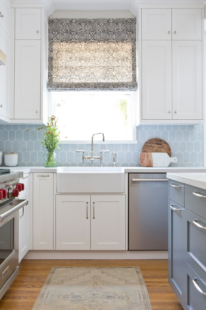 Photo of a mid-sized transitional kitchen in San Francisco with a farmhouse sink, shaker cabinets, blue splashback, ceramic splashback, stainless steel appliances, with island and medium hardwood floors.