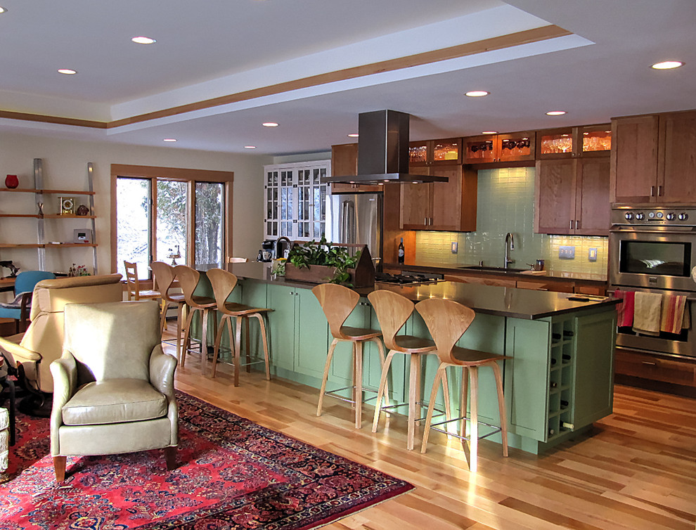 Mid-sized transitional galley light wood floor kitchen photo with quartz countertops, glass tile backsplash, stainless steel appliances, an undermount sink, shaker cabinets, medium tone wood cabinets, green backsplash and an island