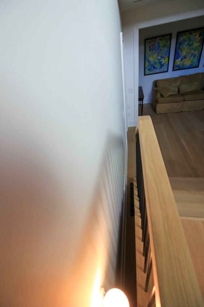 Cette image montre un très grand escalier flottant minimaliste avec des marches en bois, un garde-corps en matériaux mixtes et du lambris de bois.