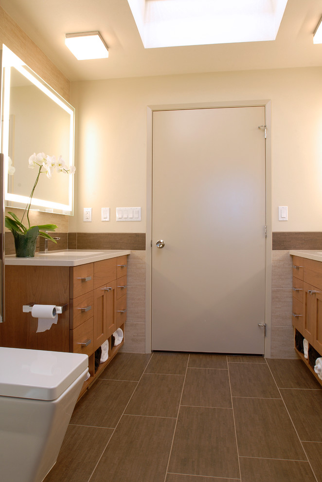This is an example of a small contemporary master bathroom in Seattle with an undermount sink, flat-panel cabinets, light wood cabinets, engineered quartz benchtops, a drop-in tub, an alcove shower, a one-piece toilet, beige tile, porcelain tile, beige walls and porcelain floors.