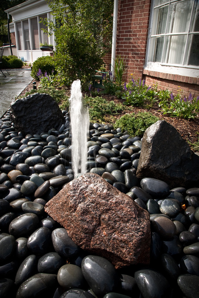 Photo of a mid-sized modern backyard patio in Milwaukee with a water feature and gravel.
