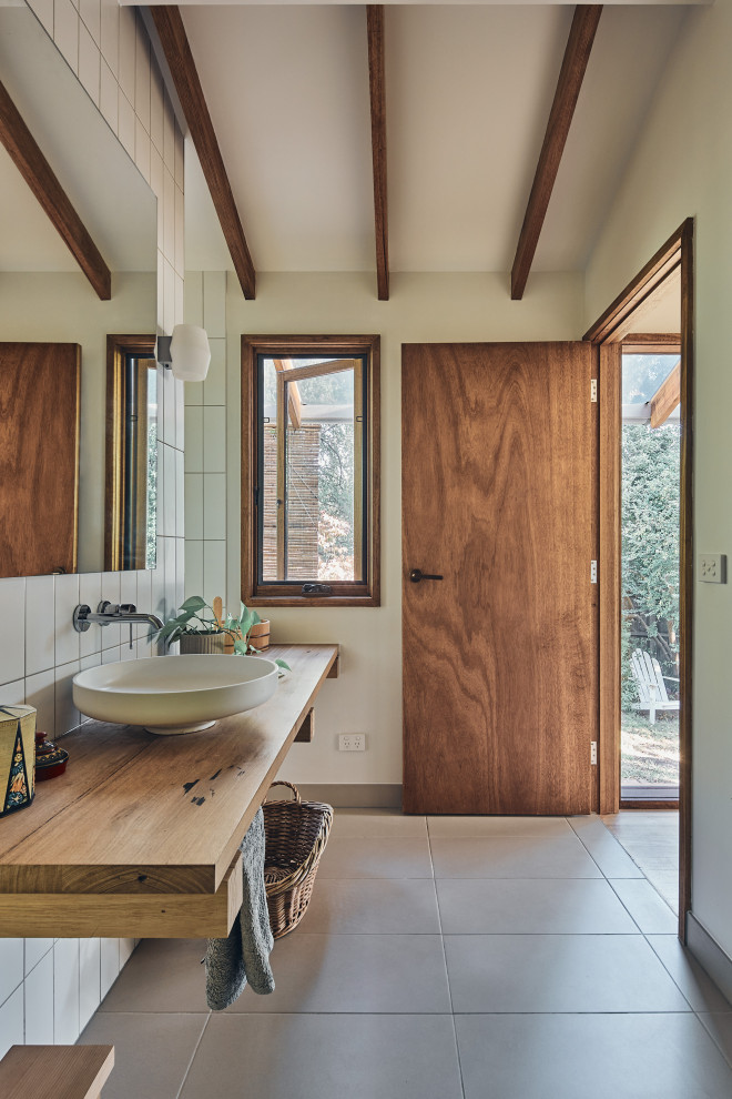 На фото: ванная комната в восточном стиле с фасадами цвета дерева среднего тона, японской ванной, столешницей из дерева и балками на потолке