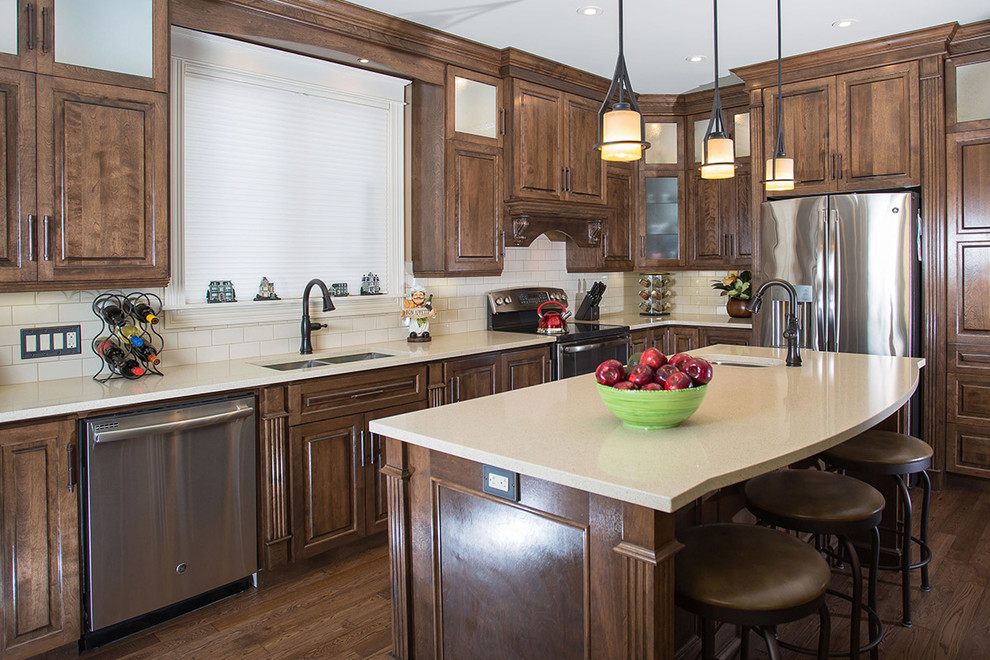 Inspiration for a mid-sized rustic dark wood floor kitchen remodel with raised-panel cabinets, dark wood cabinets, white backsplash, subway tile backsplash, stainless steel appliances, an island and an undermount sink