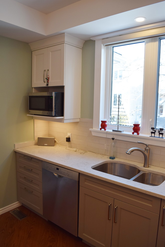 Eat-in kitchen - mid-sized transitional l-shaped medium tone wood floor eat-in kitchen idea in Toronto with an undermount sink, shaker cabinets, white cabinets, quartz countertops, white backsplash, subway tile backsplash, stainless steel appliances and a peninsula