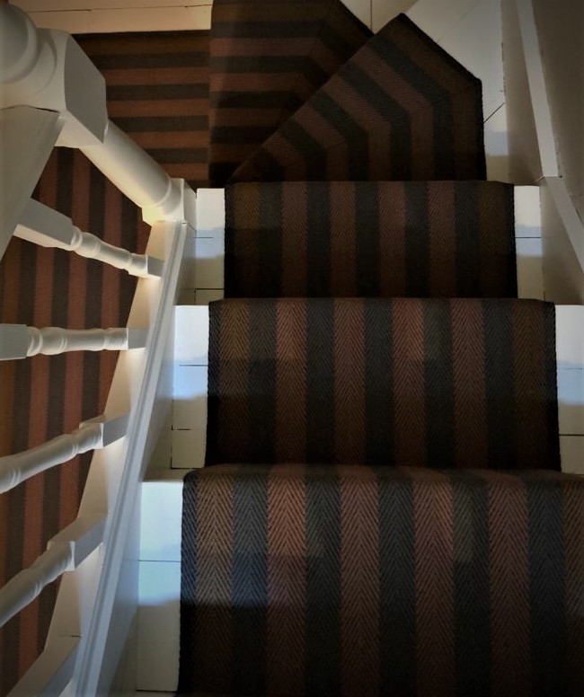 Imagen de escalera suspendida contemporánea grande con escalones enmoquetados, contrahuellas enmoquetadas y barandilla de madera